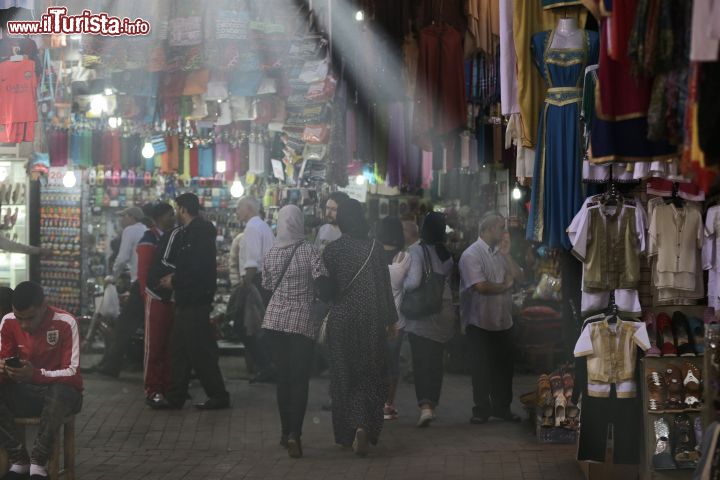 Immagine Gente nel souk di Marrakech, Marocco - Si trova nel cuore di questa città marocchina il più grande mercato tradizionale berbero, noto come souk, di tutto il paese. Vi si possono trovare oggetti tipici come tappeti, babbucce, gioielli e monili, ceramiche e spezie, ma anche moderna tecnologia di consumo. Contrattare il prezzo di acquisto di un oggetto è una prassi a cui non ci si può sottrarre così come accettare l'invito a sorseggiare un buon the alla menta 