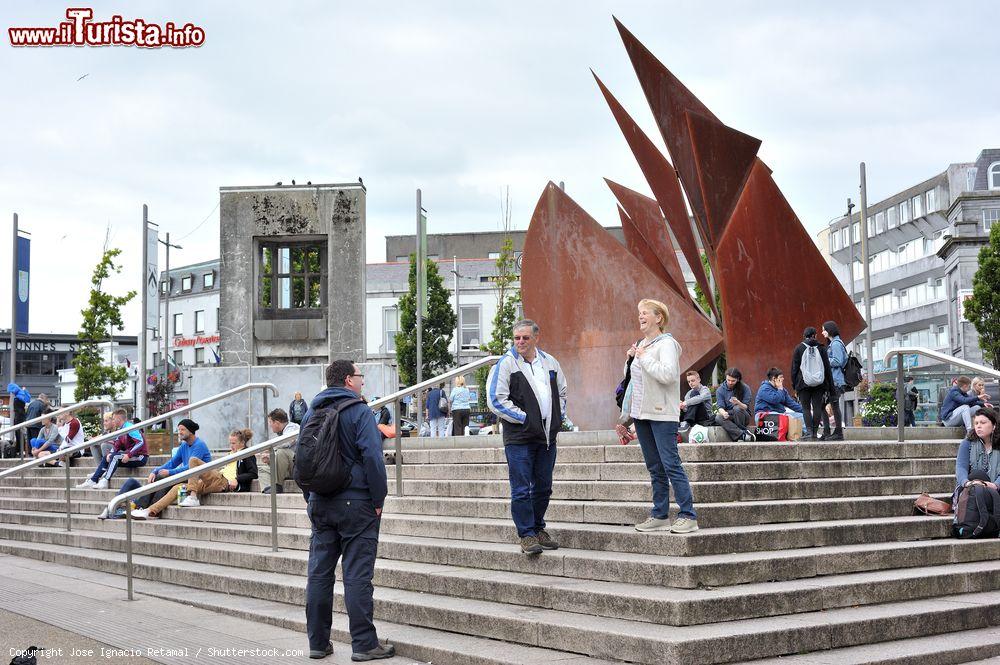 Immagine Persone in Eire Square nel centro di Galway, Repubblica d'Irlanda. Questo bel parco pubblico cittadino, noto anche come John F. Kennedy Memorial Park, è circondato su tre lati da strade che formano la principale arteria viaria di Galway. Dal 2006 il lato ovest della piazza è stato pedonalizzato - © Jose Ignacio Retamal / Shutterstock.com