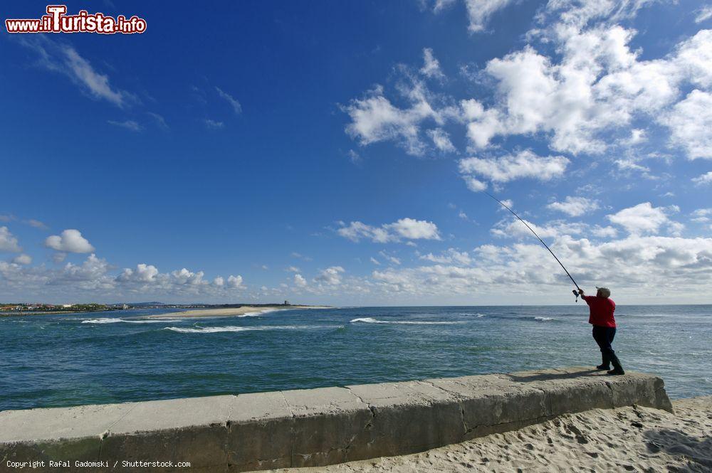 Immagine Un pescatore sul bordo dell'oceano a Esposende, Portogallo. Sullo sfondo, la sabbia del Parco Naturale del Litorale Nord - © Rafal Gadomski / Shutterstock.com