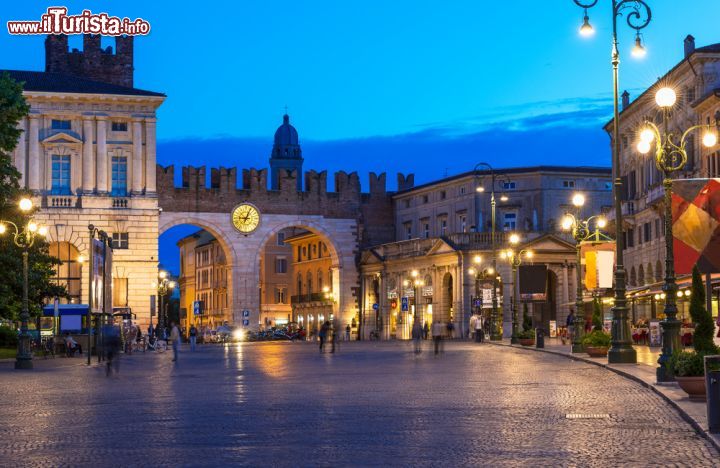 Immagine Piazza Bra a Verona - La parte più dolce e per certi versi anche nostalgica di Verona. Qui è meravigliosa l'ora del crepuscolo, poiché si accendono i lampioni generosi, l'orologio posto sotto i due archi ricorda un'atmosfera meravigliosamente retrò e le insegne dei negozi commerciali si spengono per lasciare spazio alla magia. In effetti, come si vede dall'immagine, qui trionfa un clima da fiaba - © Catarina Belova / Shutterstock.com