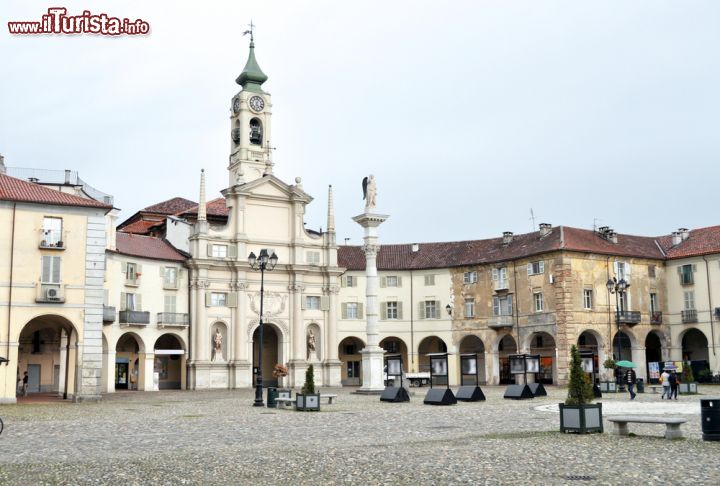 Immagine Fotografia panoramica di Piazza dell'Annunziata a Venaria Reale, Torino (Piemonte) - Sontuosa e raffinata nonostante rifletta completamente lo spirito barocco più eccessivo, questa Piazza oltre ad essere il cuore urbano della zona è anche un eccellente esempio di capolavoro edilizio. Le esedre che ne abbracciano la vista sono accompagnate da solenni colonne che si ergono, come si nota dall'immagine, in tutta la loro sovrastante maestosità, dando allo scenario un'idea di magnificenza e sobrietà al tempo stesso, viste le tinte cromatiche tendenti alle sfumature del bianco che non risultano mai fastidiose - © s74 / Shutterstock.com