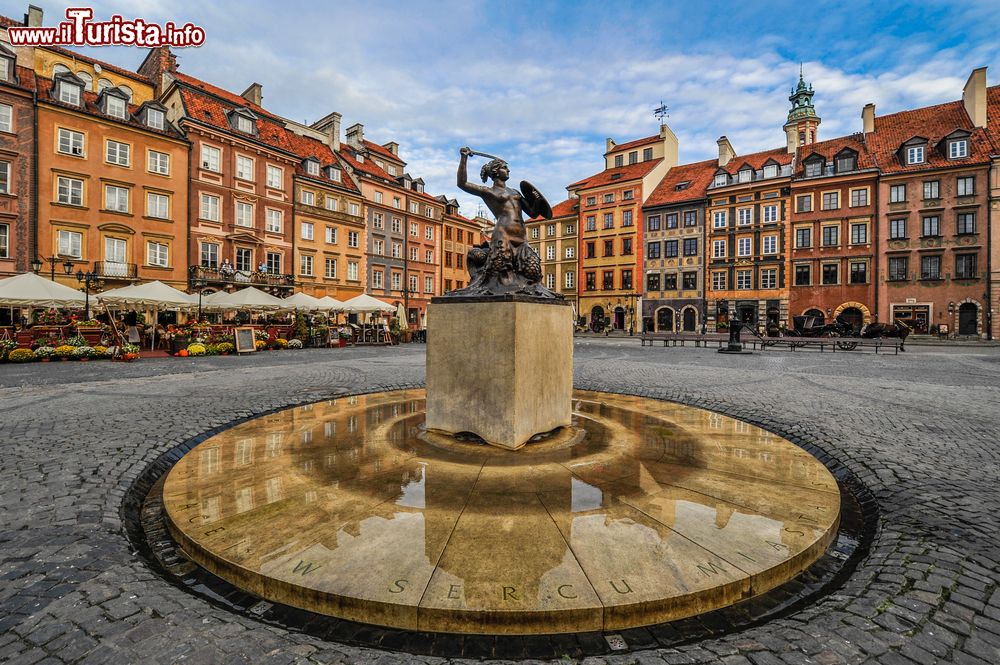 Immagine Uno scorcio del centro storico di Varsavia, Polonia. Sulla centrale piazza del Mercato si affacciano edifici a tinte pastello e caffé con tavolini all'aperto.