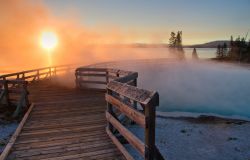 Alba nello Yellowstone National Park: passerella in un campo fumante di  geyser - © Aleix Ventayol Farrés / Shutterstock.com