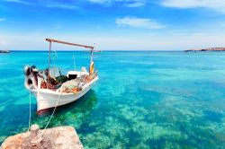 Una barca di pescatori a Formentera, al largo della spiaggia di Es Pujols, una delle più vivaci e scatenate dell'isola. Di giorno ci si gode l'acqua turchese e trasparentissima, ...