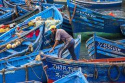 Barche colorate e pescatore a Essaouira, Marocco ...