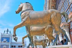 I cavalli bronzei di San Marco a Venezia. Sullo sfondo la Torre dell'orologio con i due Mori - © totophotos / Shutterstock.com