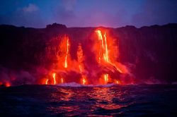 Isola di Hawaii, nell'omonimo arcipelago del Pacifico: colate di lava lungo la costa rocciosa che si tuffano in mare. Di notte il contrasto cromatico tra il fuoco e il buio è uno ...
