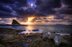 Tramonto scenografico lungo la costa di Nagasaki, Giappone, con nuvoloni plumbei trafitti dal sole - © TOMO / Shutterstock.com