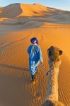 Escursione con un dromedario sulle dune di Merzouga in Marocco. Il momento migliore per compiere il tour è la mattina presto al momento dell'alba, quando il sole sempra sorgere d ...