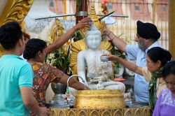 Fedeli aspergono statua del Buddha alla Shwedagon Paya di Yangon, Birmania.