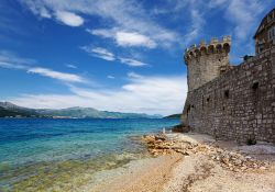 Forte di Korcula, lungo la cinta muraria del borgo, e il mare limpido di una delle spiagge più spettacolari della Croazia e delle isole della Dalmazia - © OPIS Zagreb / Shutterstock.com ...