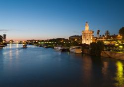 Siviglia al tramonto sul fiume Guadalquivir, sullo sfondo il Ponte Triana e sulla destra la Torre dell'Oro - © eska2005 / Shutterstock.com