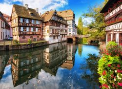Il fascino delle case storiche di Strasburgo, Francia - Dimore a graticcio colorate e ricoperte di gerani fioriti si riflettono sulle acque dei canali che attraversano la Petite France, piccola ...