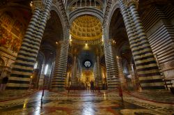 L'interno del Duomo di Siena è diviso in tre navate da alti pilastri. Sopra la navata centrale e il coro corre una balaustra dove sono disposti ben 171 busti di papi scolpiti da vari ...