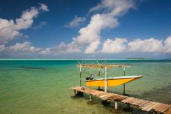 Isola di Maupiti, arcipelago delle Isole della Società, Polinesia Francese: una piccola barca ormeggiata al molo di legno, nel turchese dell'Oceano Pacifico, forse pronta per andare ...