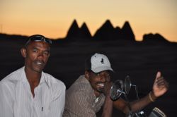 Motociclisti sudanesi al tramonto al Gebel Barkal a Karima. Sullo sfondo le piramidi