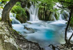 Una cascata del Parco Nazionale di Plitvice, Croazia - Tra un laghetto e l'altro, l'acqua azzurra cristallina di Plitvice scorre impetuosa rendendo ancora più selvaggio e incontaminato ...