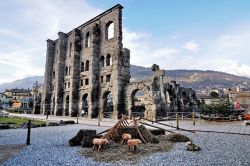 Presepe rustico al mercatino Natale di Aosta, sullo sfondo il Teatro Romano