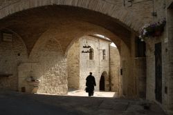 Un prete a passeggio nel borgo storico di Assisi in Umbria. Visitare la città dove nacque e visse il santo patrono d'Italia ha un importante significato storico e artistico oltre ...