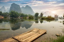 Rafting sul fiume con una zattera di canne da bambù: ci troviamo a Yangshuo un villaggio non distante da Guilin, nella Cina meridionale - © asharkyu / Shutterstock.com