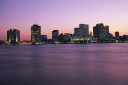 Skyline di New Orleans al tramonto, Louisiana -  Una suggestiva immagine panoramica della skyline della città con il fiume Mississipi, su cui sorge, in primo piano. Città ...