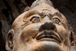 Primo piano di una statua di Budda nelle grotte di Longmen a Luoyang in Cina. Le grotte hanno subito un grave saccheggio all'inizio del XX secolo e durante la rivoluzione maoista - © ...