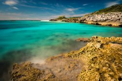Affioramento roccioso ai piedi di una spiaggia a Little San Salvador Island, Bahamas. Nota anche come Half Moon Cay, è una delle circa 700 isole che compongono l'arcipelago delle ...