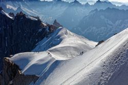 Alpinisti sui monti innevati di Chamonix, Francia: in discesa dalla funivia dell'Aiguille du Midi verso il ghiacciaio.

