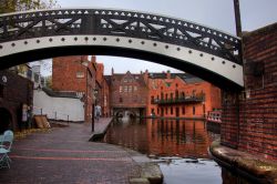 Canali di Birmingham e vecchi edifici nei pressi del Gas Street Basin, Inghilterra. Un grazioso ponte pedonale in ferro attraversa uno dei canali storici della città.