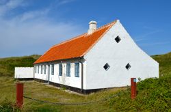 Un'antica casa bianca ristrutturata a Skagen, Danimarca. A farle da cornice la natura selvaggia e rigogliosa di questo angolo nord del territorio danese.



