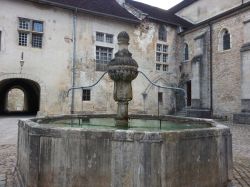 Antica fontana in una piazzetta del borgo di Perouges, Francia. Sullo sfondo, palazzi di un tempo.
