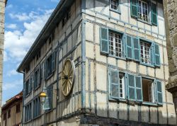 Un antico edificio nel centro di Bayonne con architettura a graticcio e la ruota in legno di un carro affissa alla facciata.
