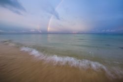 Arcobaleno all'alba sulla spiaggia di Flic en Flac, Mauritius - Un grande arcobaleno annuncia una splendida giornata di sole sopra la spiaggia di Flic en Flac sull'isola di Mauritius ...