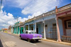 Una scena tipicamente cubana: una vecchia auto americana degli anni '50 passa davanti a case coloniali colorate e un po' malmesse a Pinar del Rio - © Fotos593 / Shutterstock.com ...