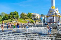 Bambini giocano nella fontana di Maidan Nezalezhnosti a Kiev, Ucraina. Independence Square ospita questa bella fontana con l'orologio di fiori e il palazzo Ottobre sullo sfondo - © ...