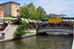 Bancarelle e tavolini dei caffè affollati lungo le strade e i ponti sui canali della citadina di L'Isle-sur-la-Sorgue, in Provenza - foto © Oleg Znamenskiy / Shutterstock.com ...