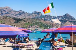 Bandiere al vento in una spiaggia di Giardini Naxos, Sicilia. Anticamente chiamata Naxos, è stata uno dei primi insediamenti greci dell'isola - © vvoe / Shutterstock.com