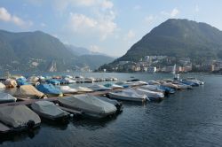 Barche ormeggiate al molo del lago di Lugano, Svizzera. Noto anche come lago Ceresio, questo bacino alpino è ramificato lungo il confine italo-svizzero.

