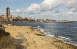 Battigia di rocce piatte durante la bassa marea a Sliema, Malta. A fare da cornice Paceville e la baia di San Giuliano - © arrowsg / Shutterstock.com