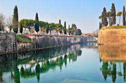 Una bella immagine del canale di Peschiera del Garda con cipressi e alberi, Veneto.



