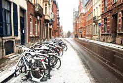 Biciclette parcheggiate lungo una strada a Leuven, Belgio, in inverno con la neve.
