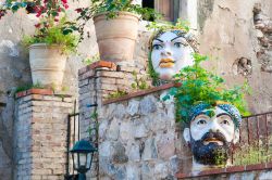 Caratteristici vasi a forma di testa incastonati nei muri di pietra lungo le vie di Castelmola, Sicilia.