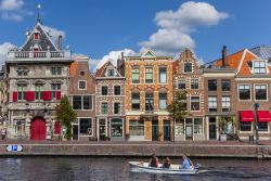 Case colorate affacciate su un canale di Haarlem, Olanda. In primo piano, una barca con persone e un cagnolino - © Marc Venema / Shutterstock.com