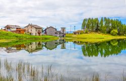 Case riflesse nel lago Lod nei pressi del villaggio di Chamois, Valle d'Aosta. Il lago si trova sotto il Monte Charvaz a 2019 metri di altitudine ed è raggiungibile con la seggiovia ...