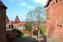 Castello di Mezzo, Malbork: siamo sul ponte d'accesso al Castello di Mezzo (Zamek średni) da dove si può scorgere, oltre gli alberi, il fiume Nogat scorrere placido. Oltre alle ...