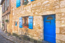 Centro di Bergerac (Francia): facciata di case in pietra con porte e finestre in legno blu.

