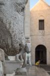 Dettaglio di una statua nei pressi del duomo di Bari, Puglia. Sullo sfondo, un uomo seduto sulla scalinata.
