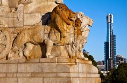 Dettaglio scultoreo al Tempio della Rimembranza di Melbourne, Australia. Il memoriale con due stuatue di leoni e, sullo sfondo, la torre Eureka - © Norman Allchin / Shutterstock.com