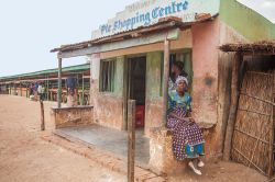 Una donna del Malawi con abiti tradizionali seduta davanti a una drogheria della città di Lilongwe - © Andrea Willmore / Shutterstock.com