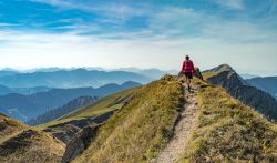 Una donna passeggia in autunno sulla cresta della catena Nagelfluh nei pressi di Oberstdorf (Germania). Sullo sfondo, la cima di Hochgrats.
